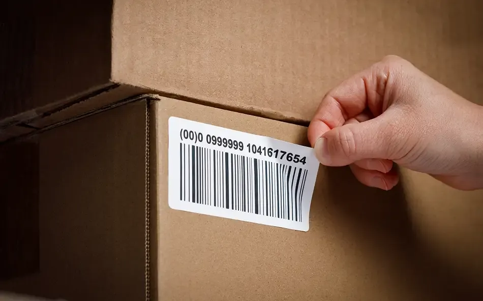 a hand peeling an LPN label off of a cardboard box