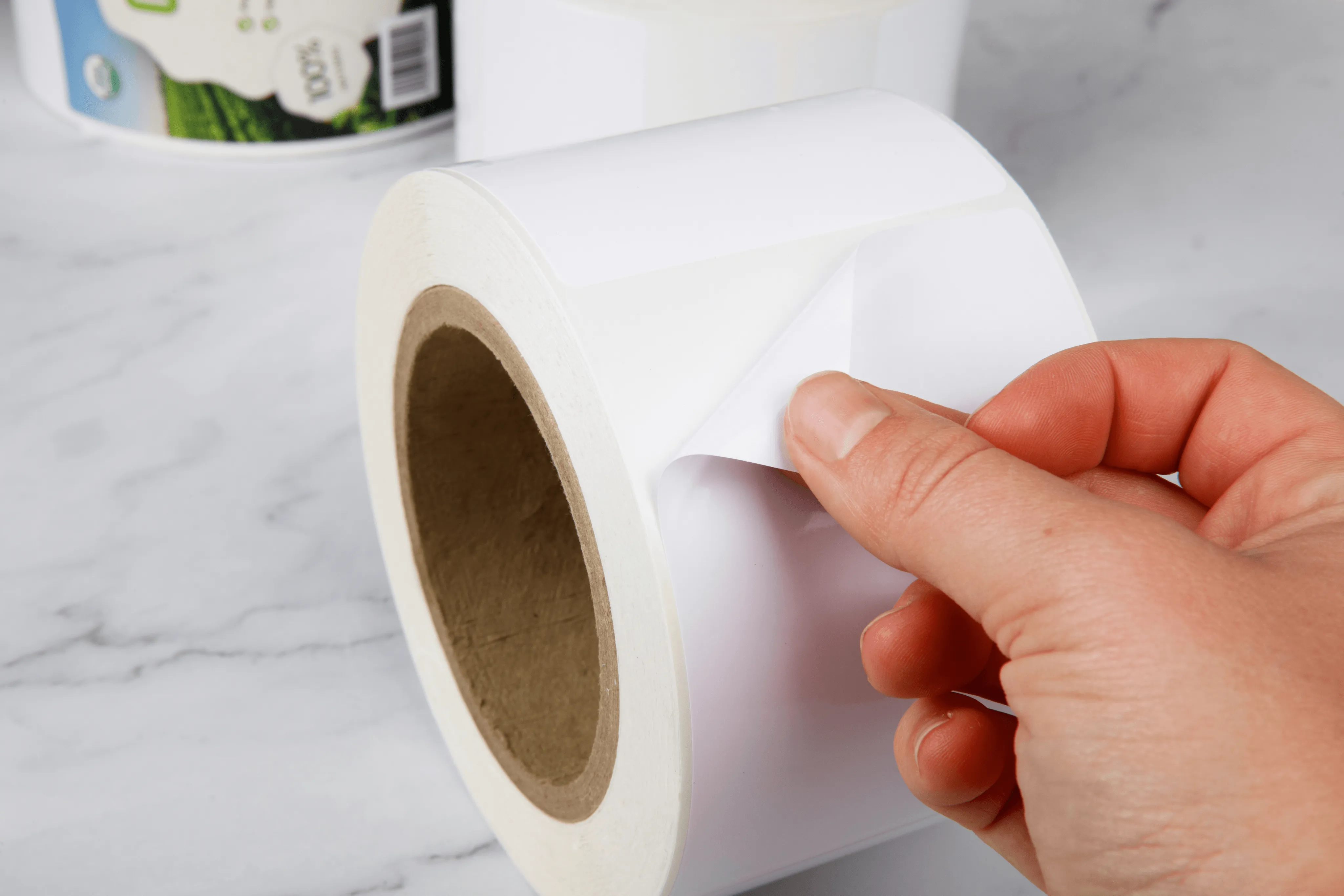 hand peeling white food and beverage labels from a roll