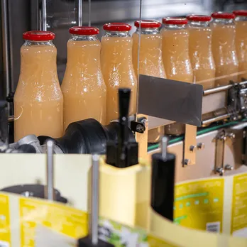 Glass bottles of juice with colorful labels in refrigerated display