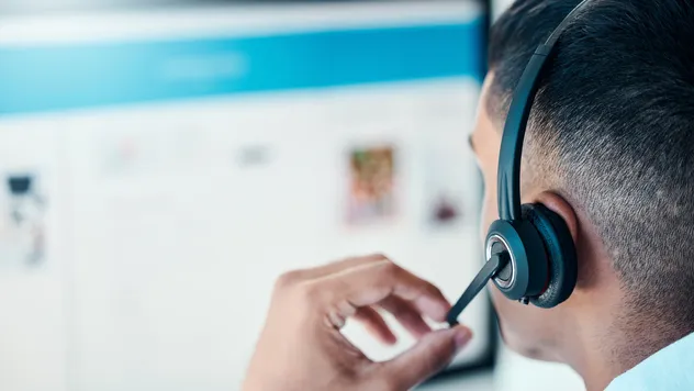An employee with a headset on looking at a monitor