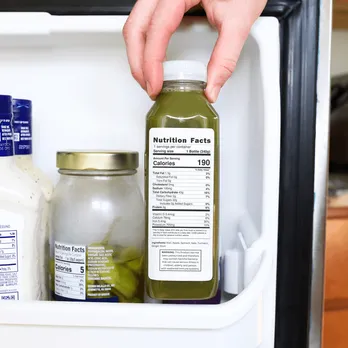 Hand placing nutrition facts labels on white product containers