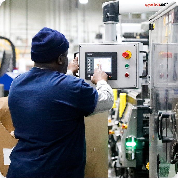 a worker interacting with the controls of a large manufacturing device