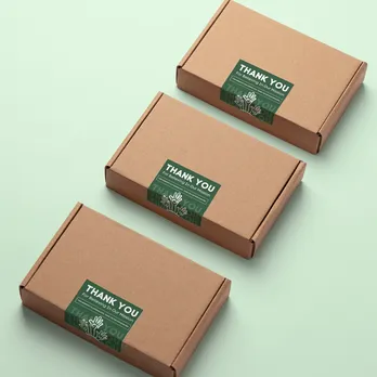 Three cardboard boxes with green custom digitally printed labels on mint green background
