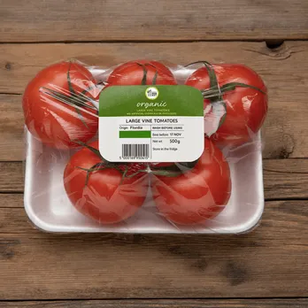 Package of fresh tomatoes with product label on wooden surface
