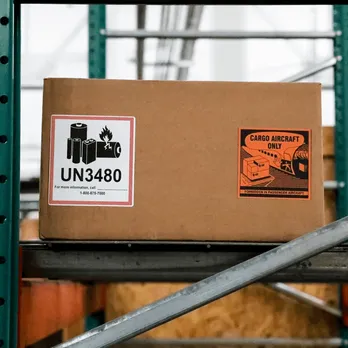 Cardboard shipping boxes with UN3400 hazmat labels and orange warning stickers