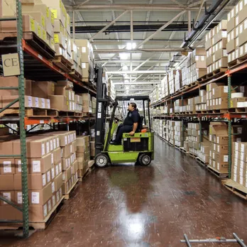 Warehouse aisle with forklift moving pallets between tall storage racks