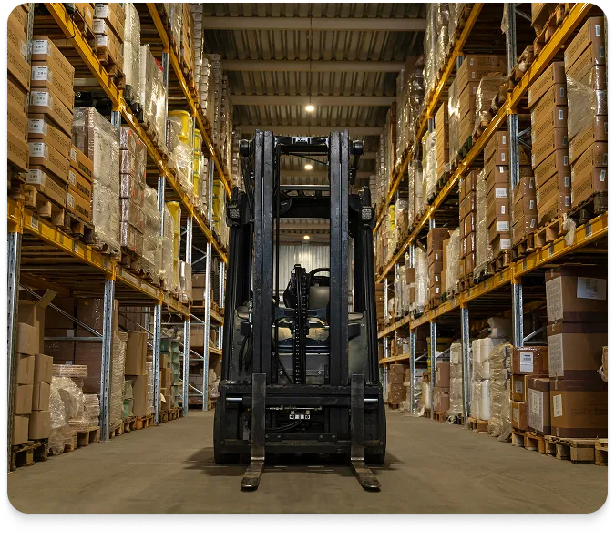 A forklift sitting in the middle of a warehouse aisle between two large walls of racks loaded with cardboard boxes